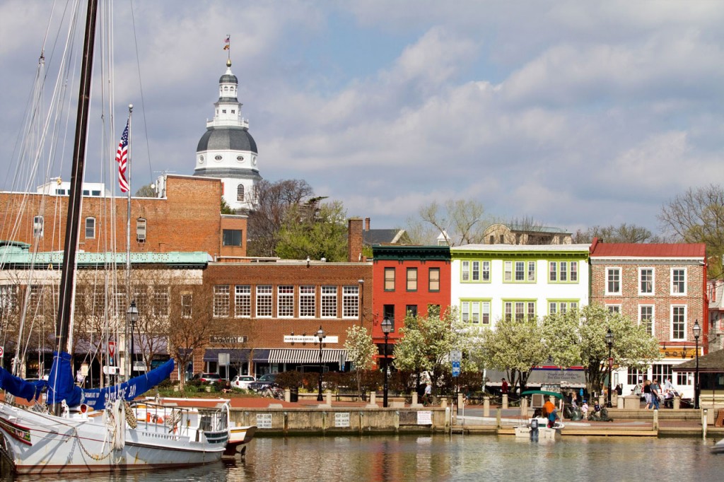 View of shops along the waterfront with the state's capitol building visible in the distance.