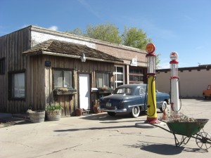 A small museum formerly a gas station with the original pumps and a classic 50s car out front.