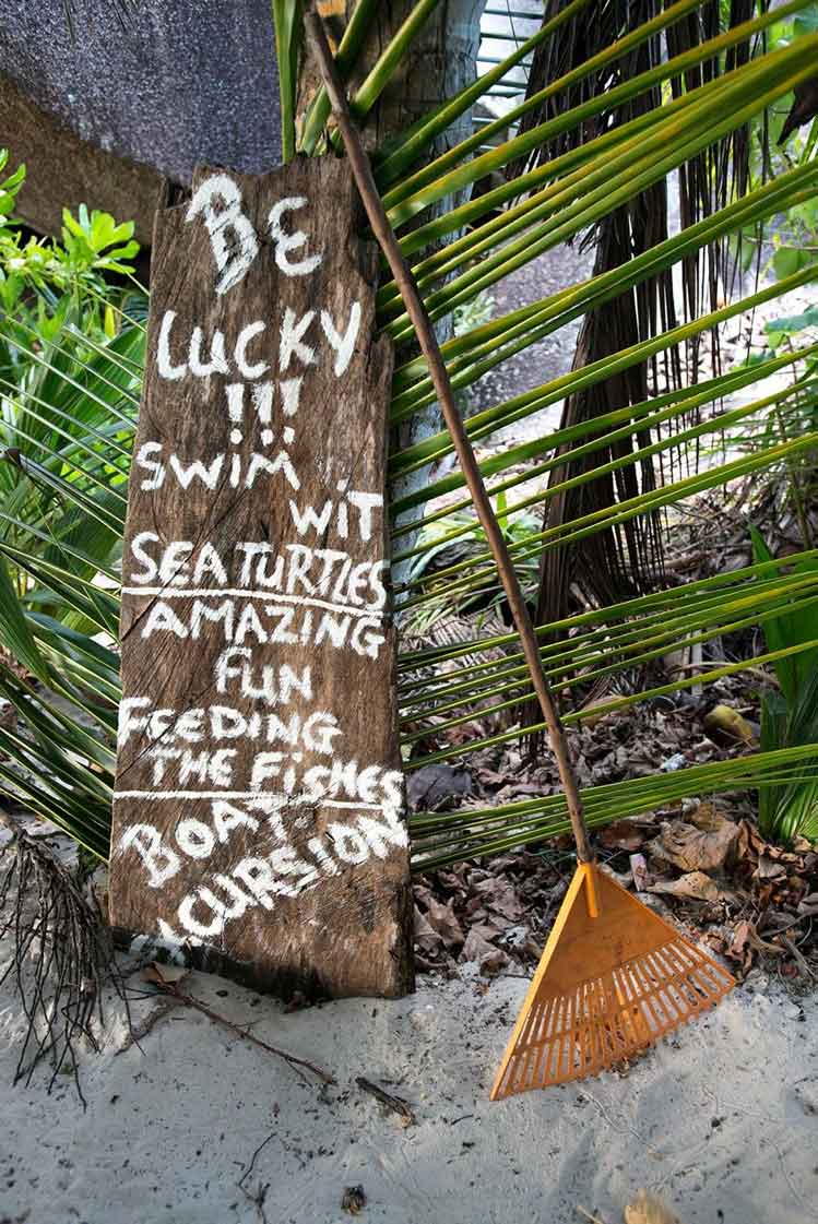 Beach sign under palm trees on the island of La Digue. Image by Oliver Berry / Lonely Planet.