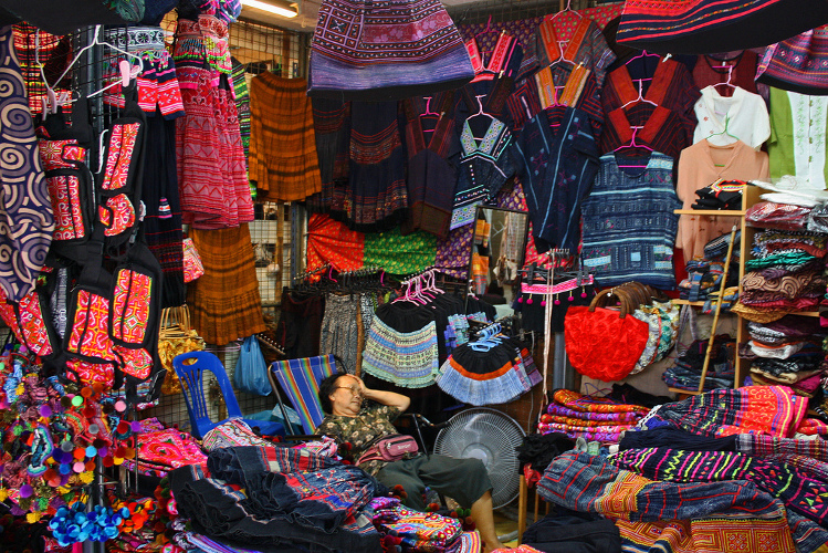 A clothing vendor enjoys a moment of respite at Chatuchak Weekend Market, Bangkok. Image by istolethetv CC BY 2.0