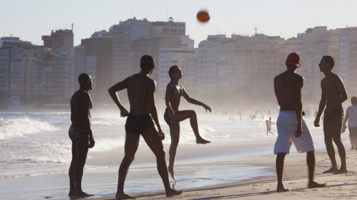 People of all ages play a hybrid of football and volleyball on Copacabana Beach.