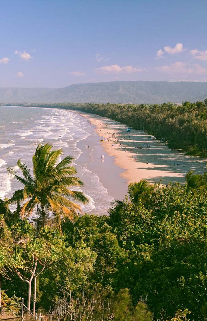 A long stretch of beach flanked by trees curves into the horizon at 4 mile beach.