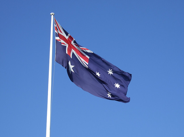 The Australian flag flies against a cloudless blue sky.