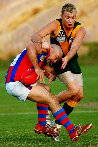 A pair of men playing Australian rules football.