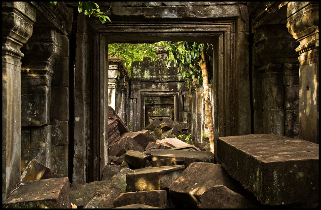 Blocky stone rubble in a temple corridor with vegetation creeping in.