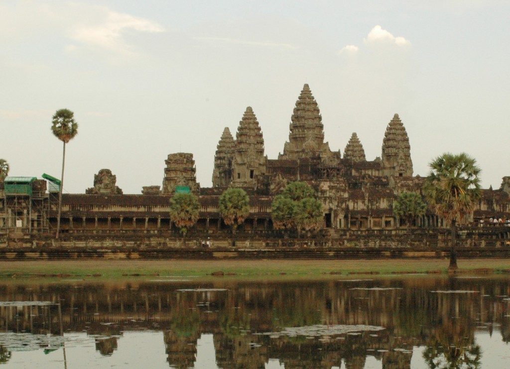 The jagged tops of Angkor Wat's temples visible across from and reflected in water.