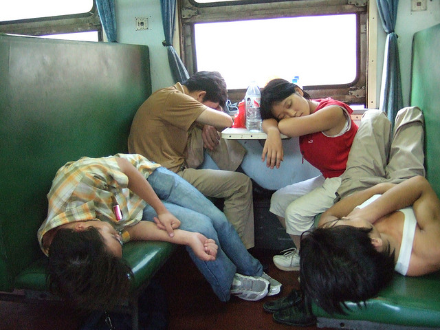 Four weary passengers sleeping on the train in "hard seat" class in China.