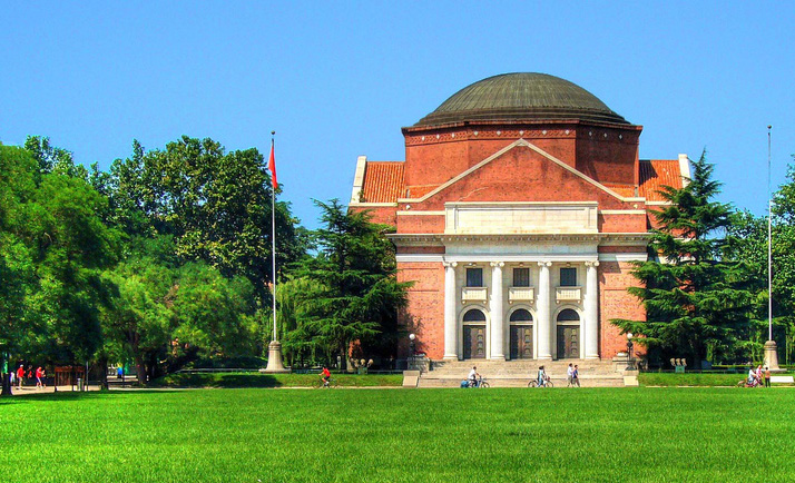 A classic domed building with four ionic pillars looks out over a wide expanse of well-maintained green lawn.