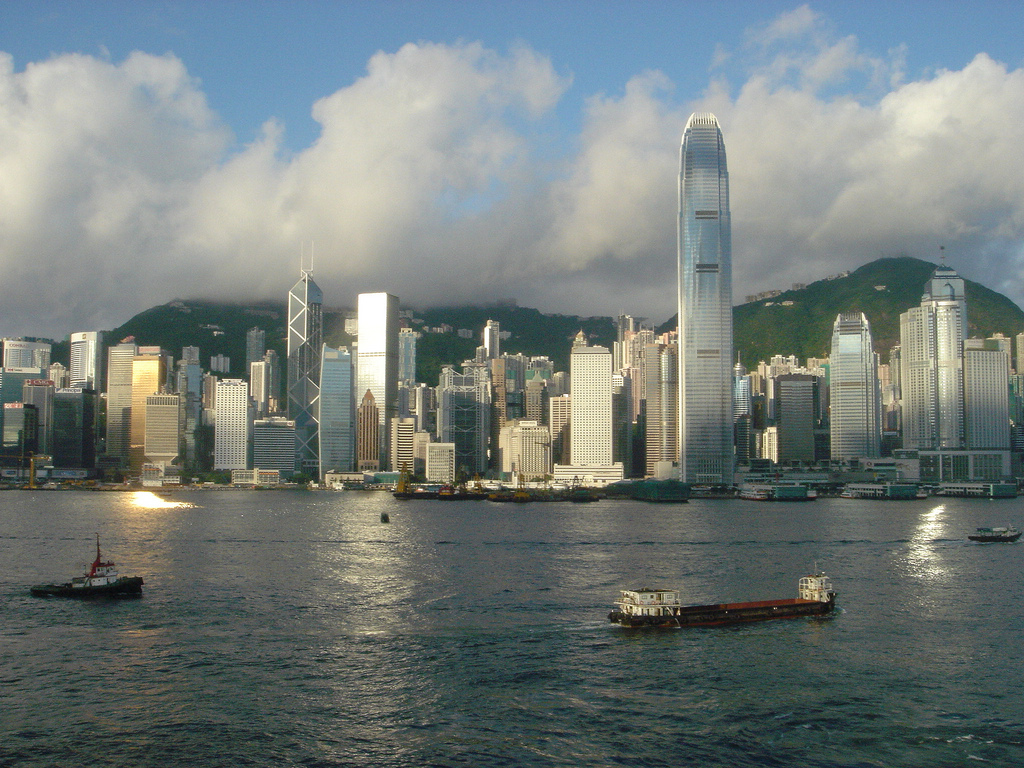 View of the cityscape across Hong Kong Harbor on a day with voluminous clouds in the sky.