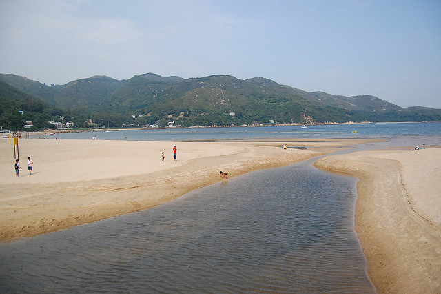 Children play in the sand along an inlet leading to the bay on Lantau Island.