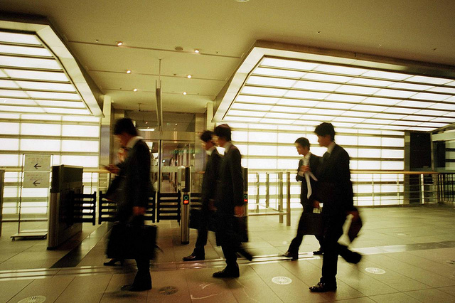 Blurred by motion, a group of businessmen in suits move through an underground walkway.