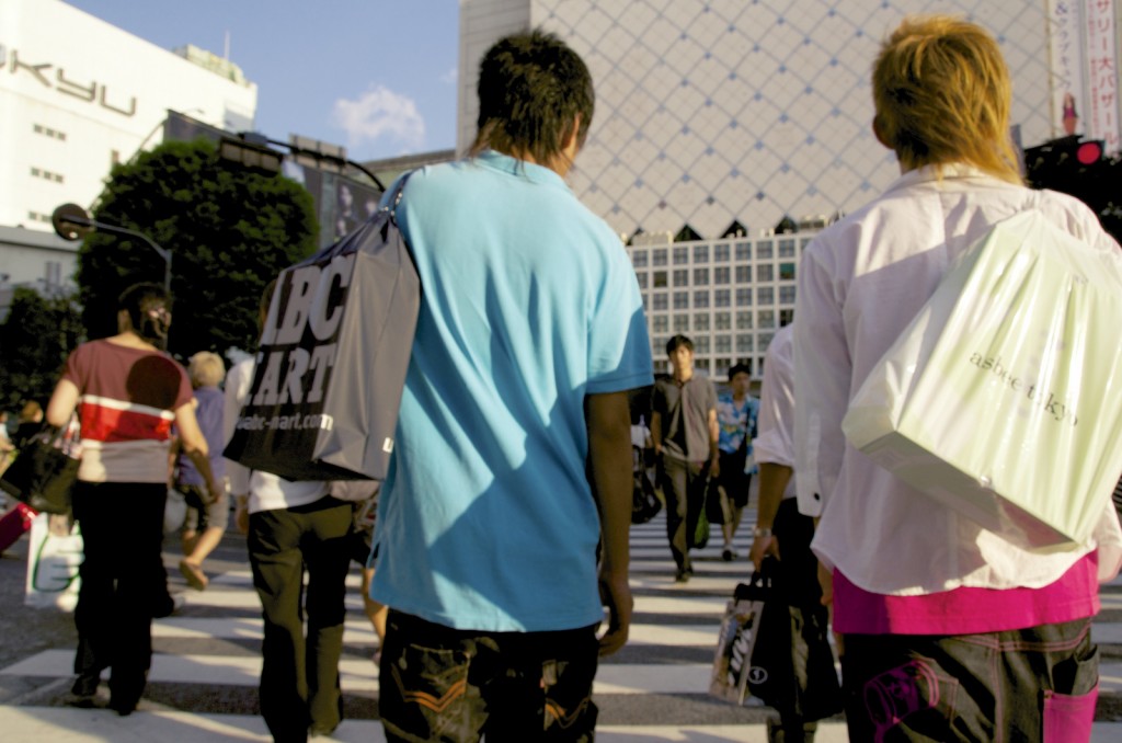 Two young men dressed in urban fashion cross at the famous busy Shibuya intersection.