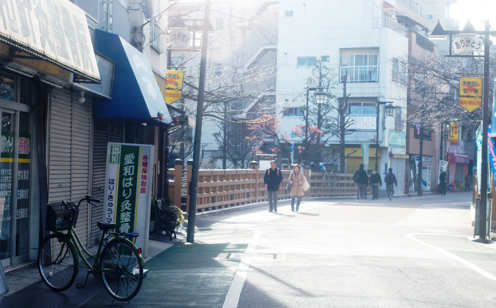 View of a quiet street with several pedestrians and a business in the foreground.