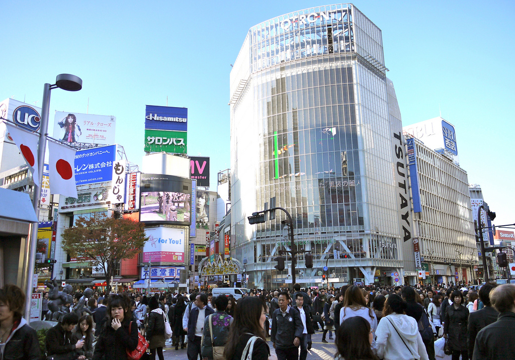 Banners on streetlights depict Japan's flag as a crowd of pedestrians go about the popular Shibuya shopping district.