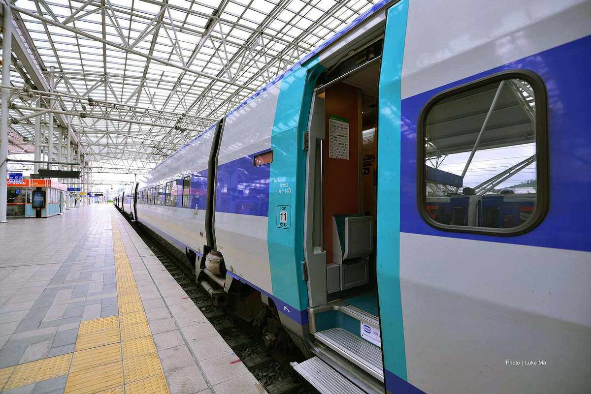 View down the platform at Seoul Station with a train waiting with open doors.