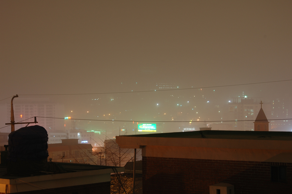 City lights shine dimly through a haze that resembles fog.