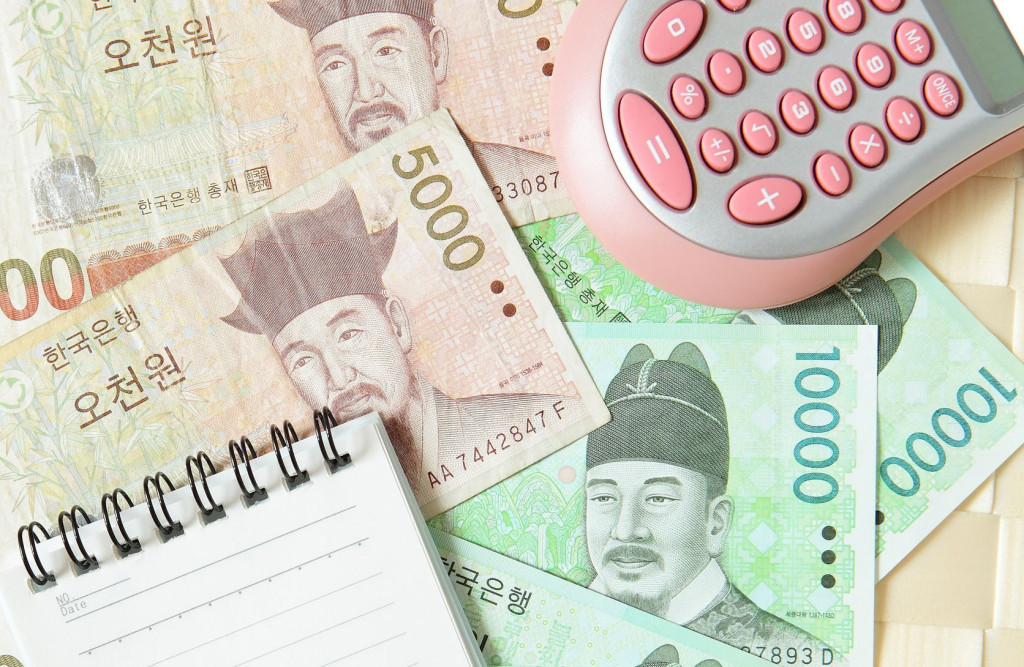 A scatter of Korean currency (won) pictured with a calculator and small notepad.
