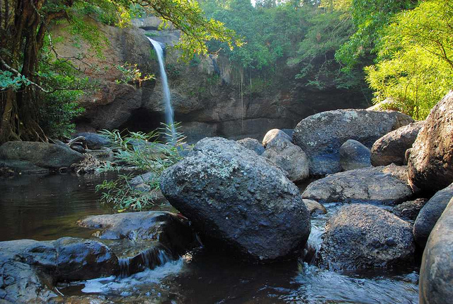 A thin waterfall streams over a ledge into a pool.