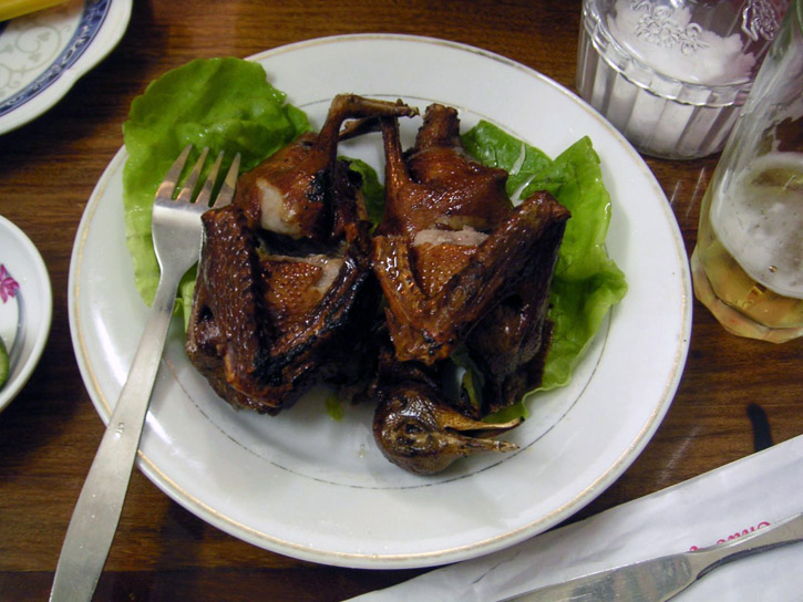 Cooked pigeons served on a bed of lettuce.