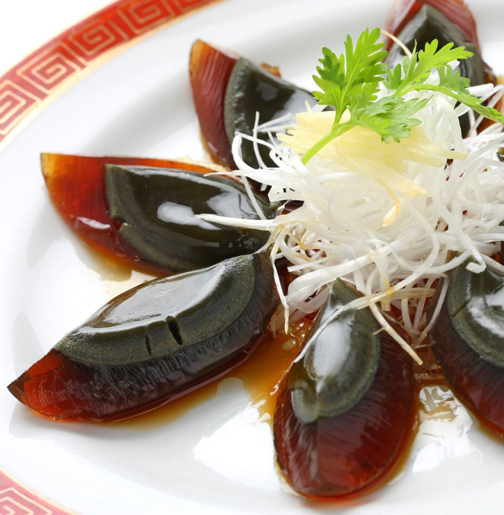 Sliced Century Eggs displayed on a plate with garnish.