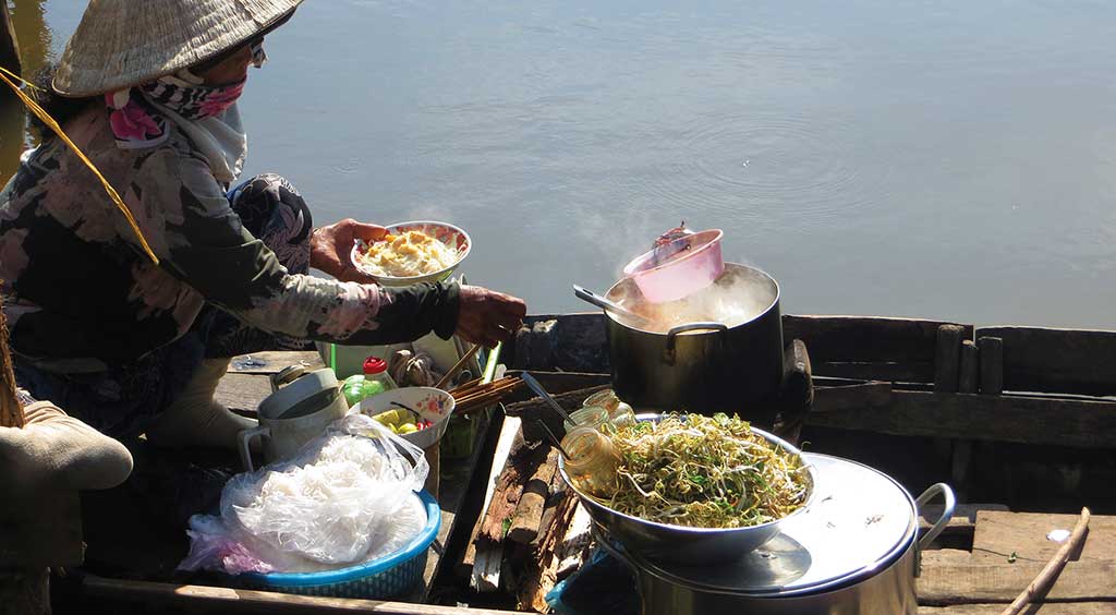 Woman ladling bun nuoc leo into a bowl. Photo © Dana Filek-Gibson.