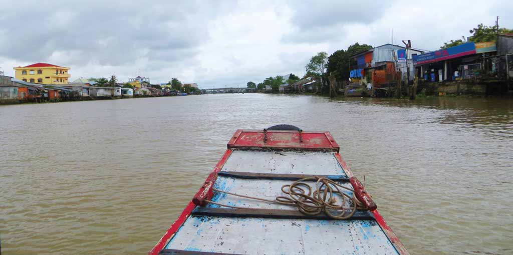 Storefronts line the banks of the Co Chien River in Vinh Long. Photo © Dana Filek-Gibson.