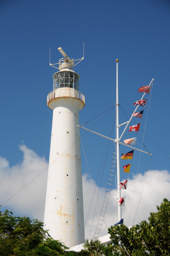 Flags fly beside a tall white lighthouse in Southampton Parish.