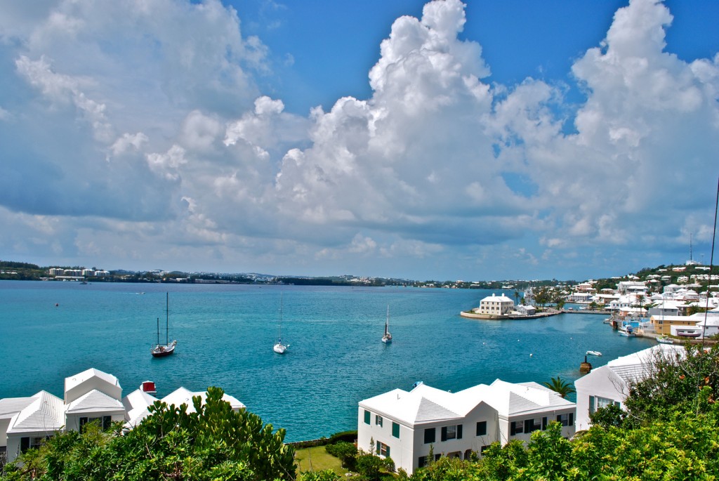 Historic white-washed houses perch along the waterfront while large clouds hang in the sky.
