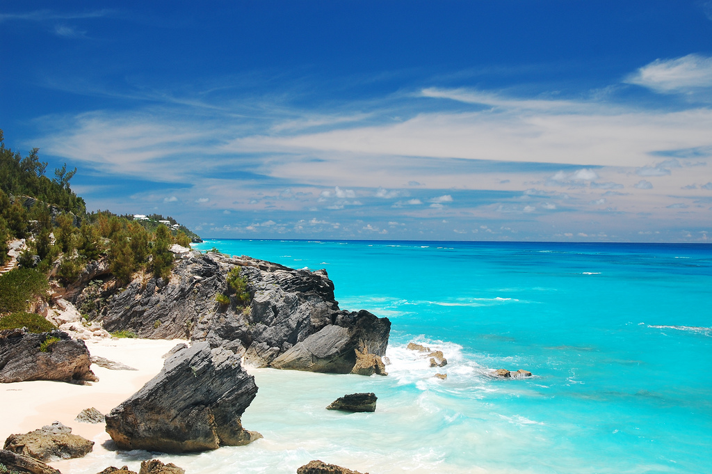 Beautiful aqua water meets a white sand beach studded with large rocks.