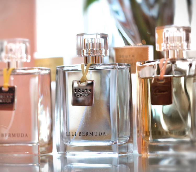 A trio of elegant looking square glass bottles of fragrance with metal stamped hang tags.