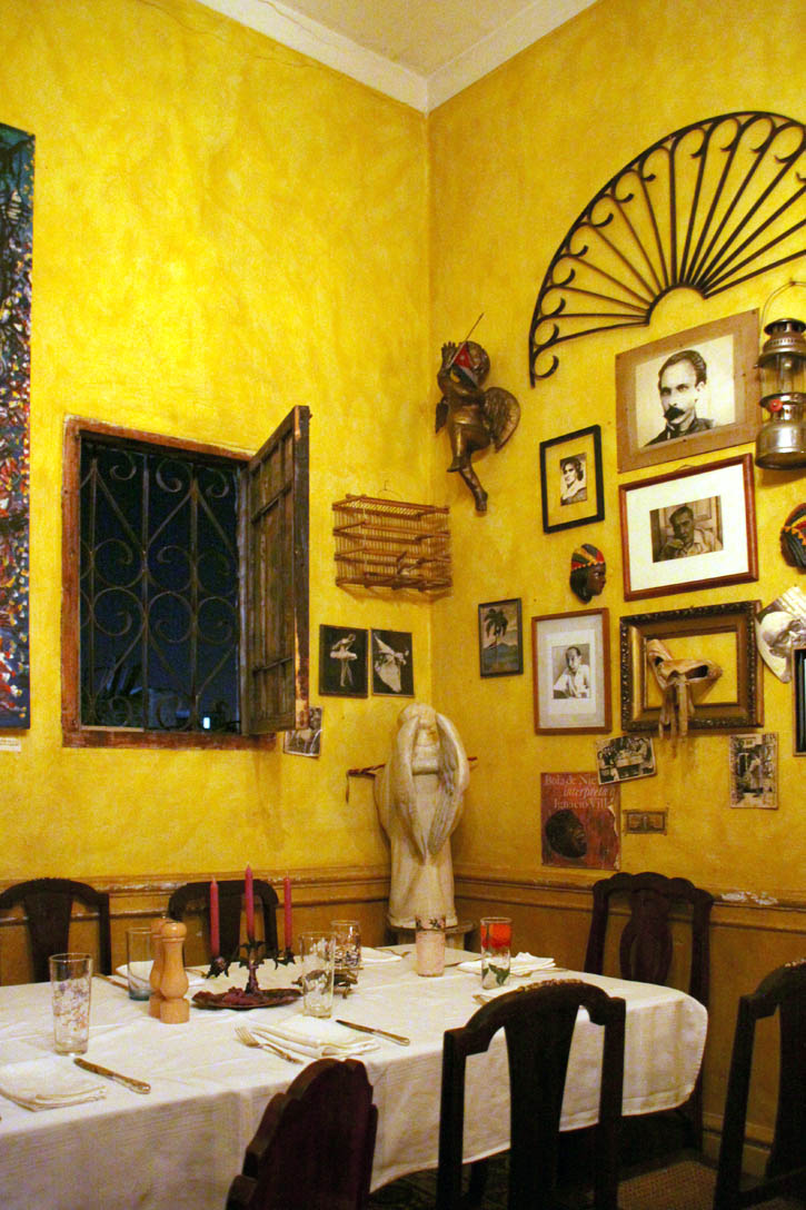 A table set for dinner in front of a wall decorated with pictures and knickknacks at La Guarida in Havana.