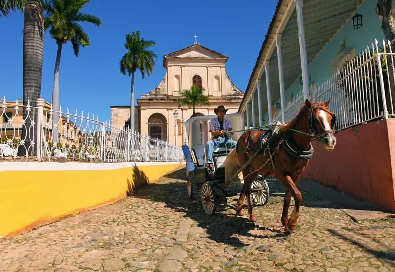 A horse-drawn buggy travels over cobblestones in Trinidad's Plaza Mayor.