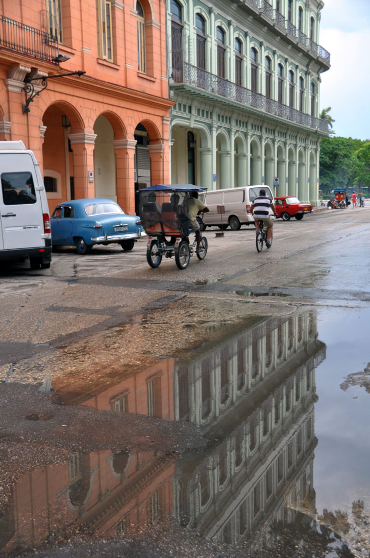 Colorful building reflect in rain puddles in Havana.