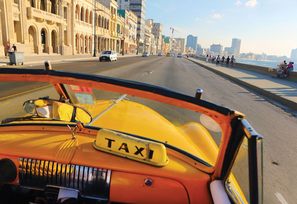 A classic convertible taxi driving down Havana, Cuba's malecon.