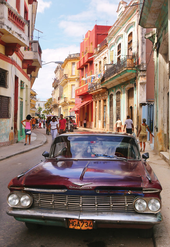 A deep purple chevy parked on the street amidst colorful buildings in Havana.