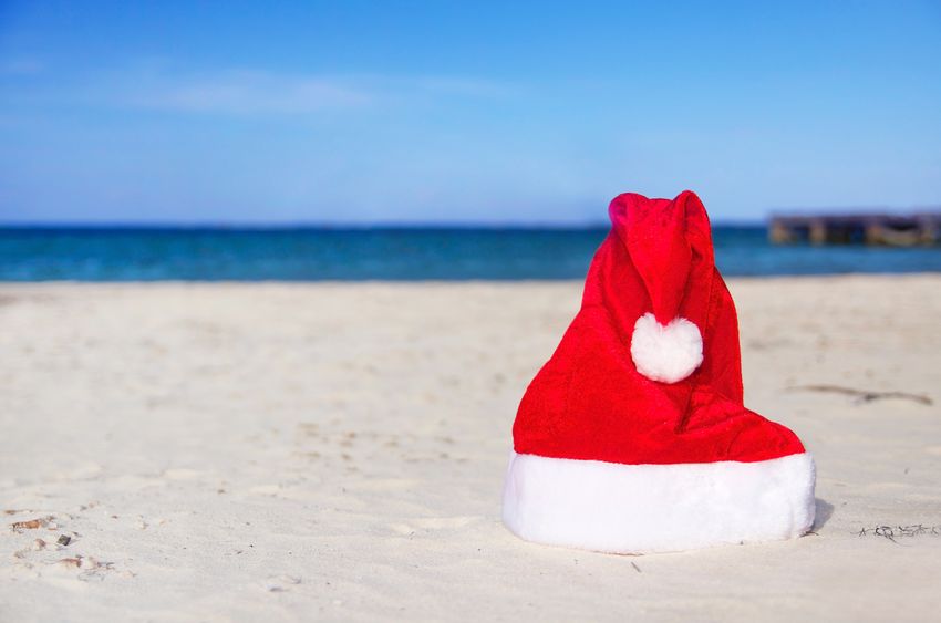 A santa hat on a white sand beach.
