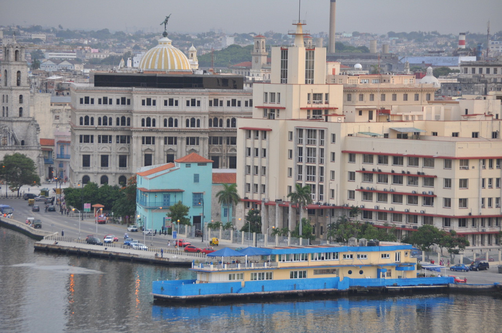 A large ferry is docked at the waterfront with multistory buildings in the background.