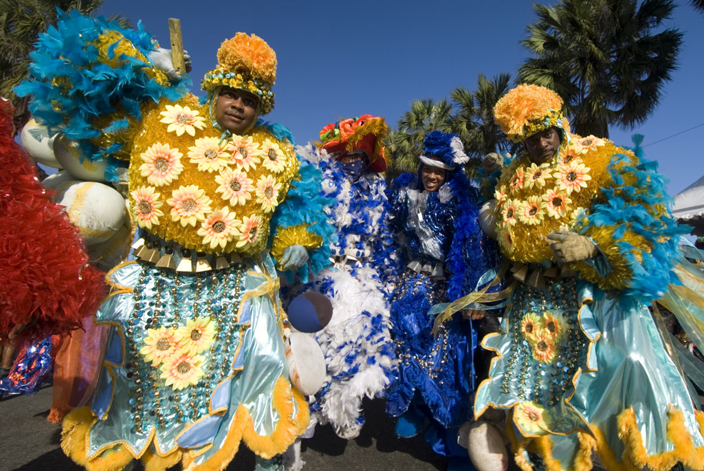 Dancers in elaborate Carnaval costumes adorned with flowers and feathers.