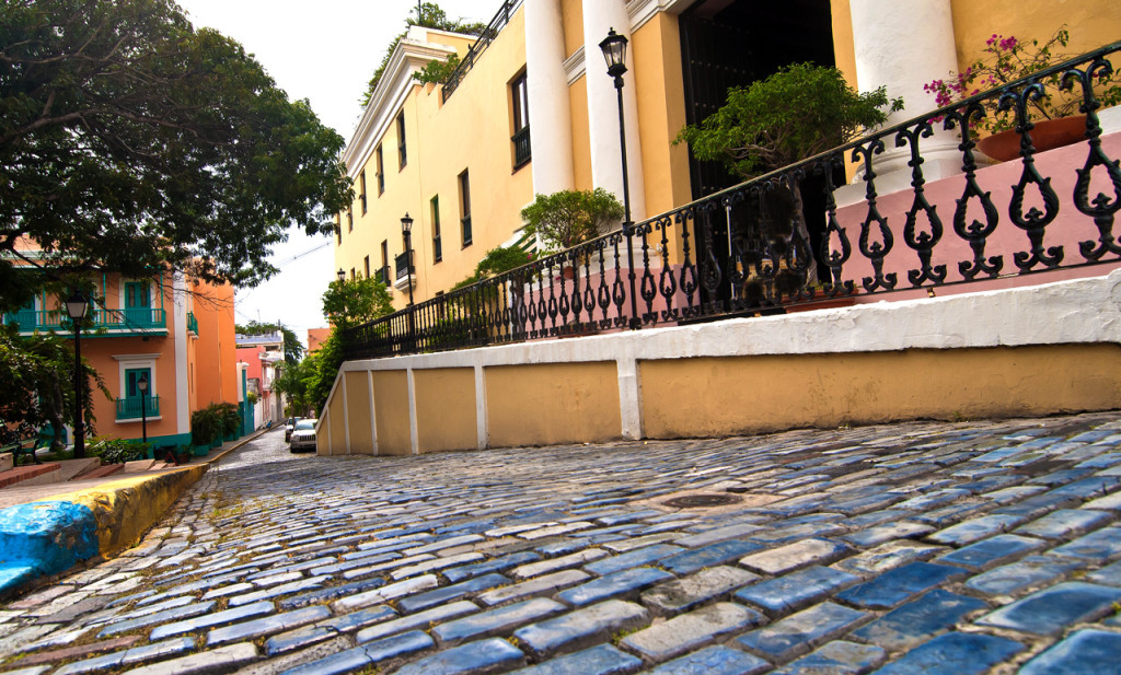Blue painted cobblestones in the foreground with a row of colonial buildings.