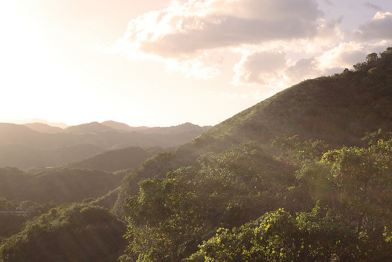 Light streams over verdant rolling mountains.