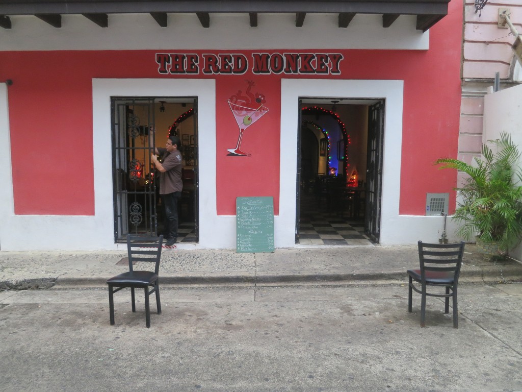 A man stands in the open doorway of the brightly painted Red Monkey bar.