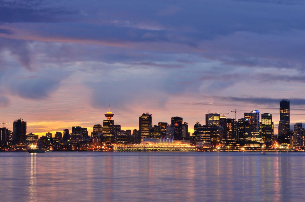 With the purple of dusk coloring the sky, Vancouver's city lights reflect in the water.