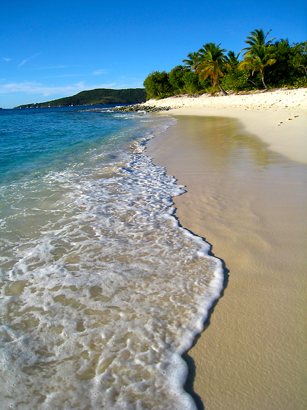 Blue ocean meets white sand on Sandy Cay's beach.