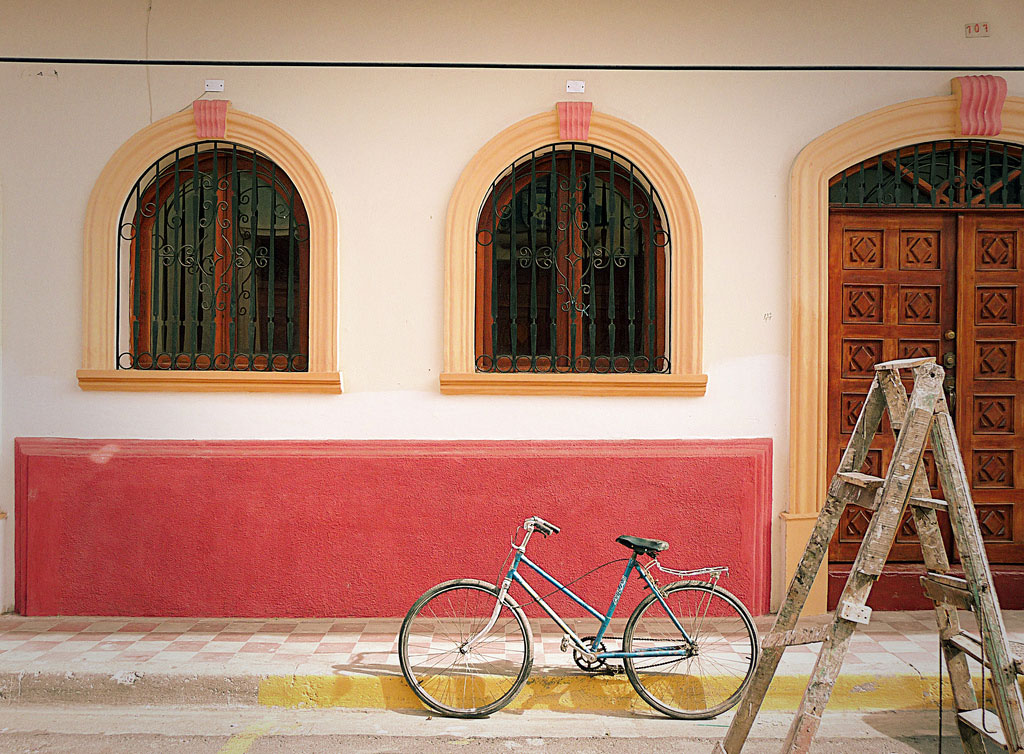 A bicycle parked on the street in front of a stucco building.