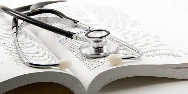 A stethoscope resting on an open medical text.