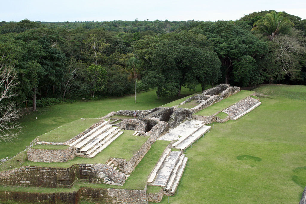 The stone steps of the Altun Ha ruins surrounded by a flat, grassy expanse.