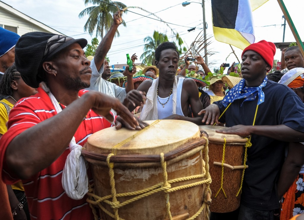 Drummers carry large drums in a crowd of revelers.
