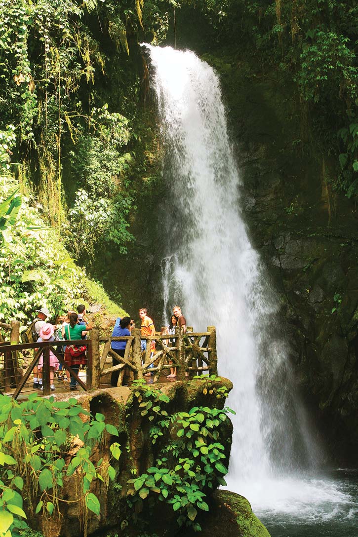 Visitors gaze at a tumbling waterfall from an observation platform.
