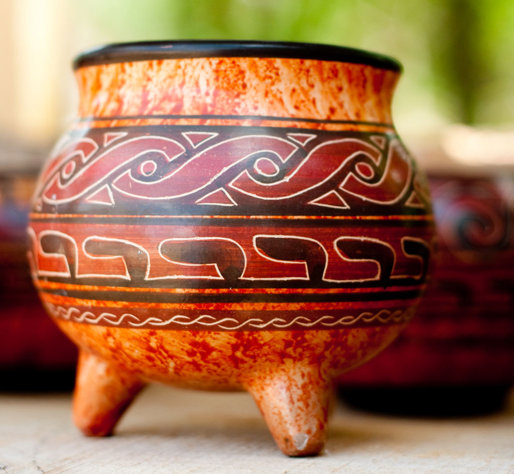 Close up photo of a hand-painted ceramic bowl with squat tripod legs.