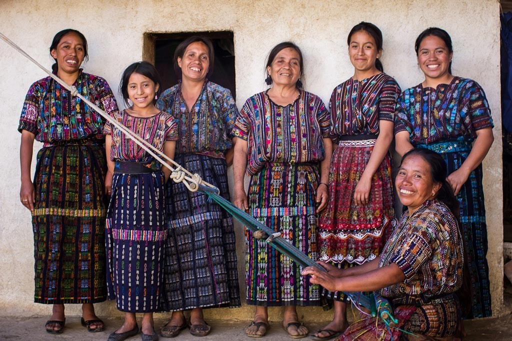 A group of Guatamalan women with a weaver working on a loom.